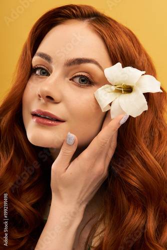 Photography Elegant young woman with red hair and flower enjoys a moment of beauty and fashi