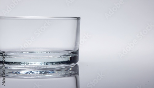 Clear glass half filled with water on a plain background