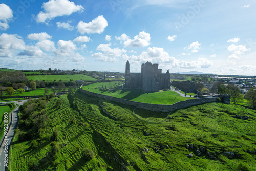 Aerial drone view of the Rock of Cashel, a historic medieval cathedral and fortress rising above the Irish countryside.