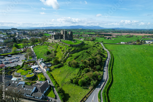 Aerial drone view of the Rock of Cashel, a historic medieval cathedral and fortress rising above the Irish countryside.
