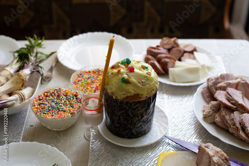 There is an Easter cake on a plate on the table. There are various products next to it.