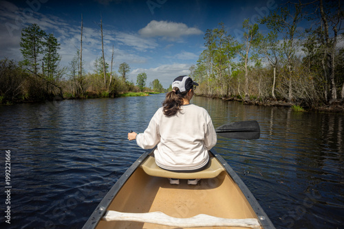 A woman paddles a canoe through the Okefenokee Swamp of Southern Georgia, USA.