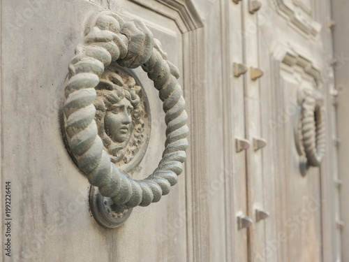 Antique stone door knocker with sculpted face on historic Italian doorway
