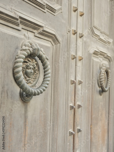 Antique stone door knocker with sculpted face on historic Italian doorway