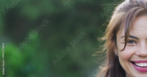 Smiling adult woman showing widening smile and crinkling eyes in park, wearing earring, copy space