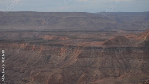 Pan across Fish River Canyon at sunset, last rays of light against rocky cliff