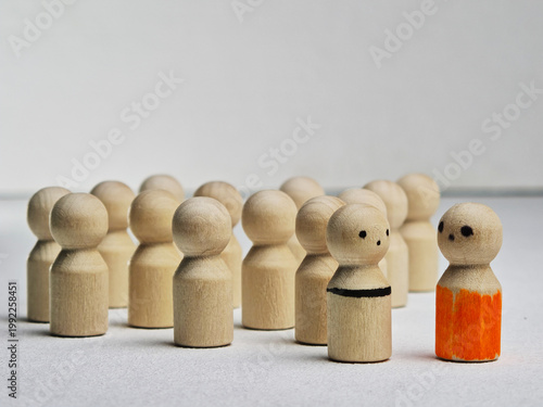 Wooden peg figures show ideas of leadership and teamwork while demonstrating the value of standing out from a group in a neutral setting