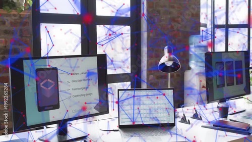 Loft desk showing monitors and laptop while network overlay moving across screens and brick wall