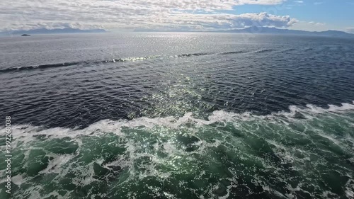 August 13, 2024 - Tracy Arm, USA - Waves and swirling water generated by a cruise ship moving through the inlet. Water surface reflects sunlight in the deep channel.