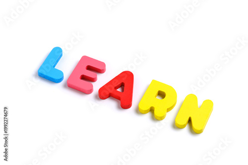 Colorful magnetic letters spelling word LEARN on clean white background, educational concept.