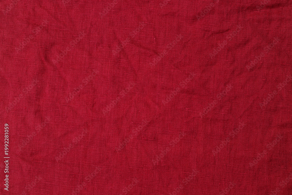 Fototapeta premium Solid red fabric with slight texture lying flat on a surface in a well-lit area during the day