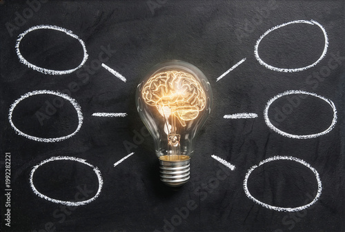 Conceptual light bulb with glowing brain inside on blackboard with chalk mind map circles.