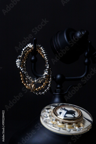 Stylish bracelets rest on vintage telephone, dark background enhances luxury feel