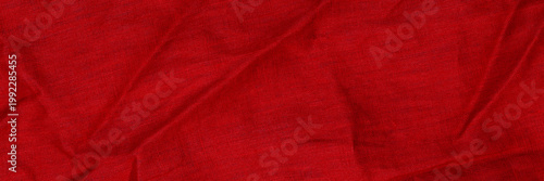 Bright red fabric with creases in texture showing folds and layers in a textile study environment during daylight hours
