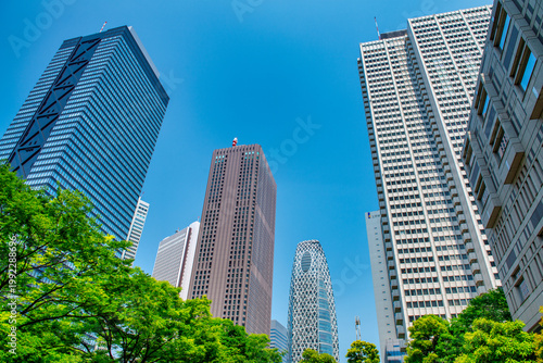 Street-level view of Shinjuku, Tokyo during spring, capturing sunlit roads, contemporary architecture, and lively city atmosphere