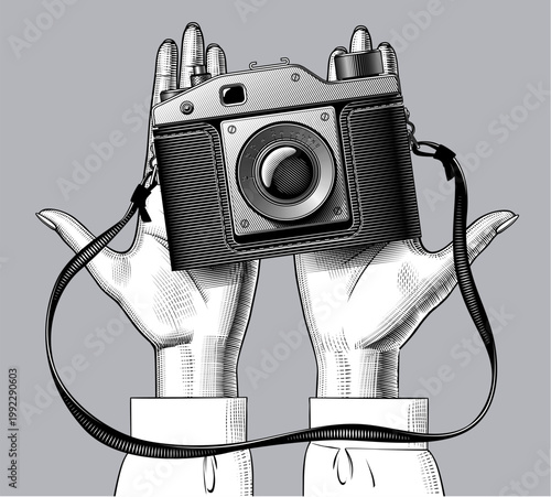 Palms of the hands with a vintage camera in front view. Detailed line art with cross-hatching shows lens, knobs, viewfinder and straps. vector illustration 
in black and white engraving style. 