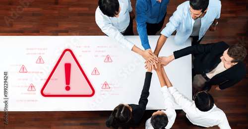 Tableau sur toile A diverse group of professionals engages in teamwork by placing their hands together on a table, symbolizing collaboration in an office setting with warning signs for awareness