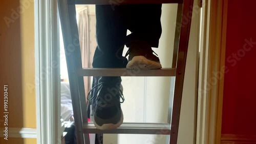 man with black jeans and trainers climbing down ladder indoors in slow motion