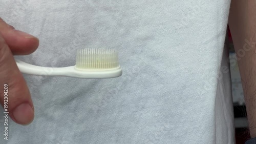 Close up of adult hands holding white toothbrush and toothpaste tube before applying paste for daily dental care