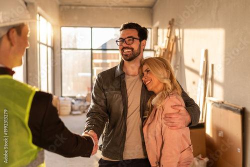 Couple meets construction manager in new home during afternoon light in modern building