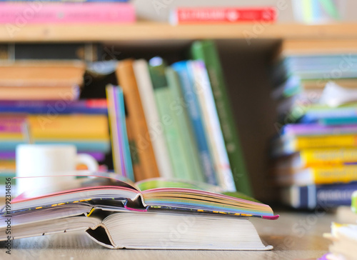 Low Angle View of Open Books on a Desk with Blurred Bookshelf and Coffee Cup Background, Bright Library and Literacy Concept for Academic Research and Higher Education