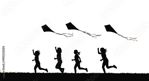 Four children run happily across a grassy field at sunset, flying their kites joyfully in the sky.