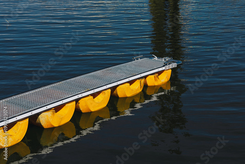 Schilderij op canvas Floating dock with yellow plastic pontoons on calm blue water