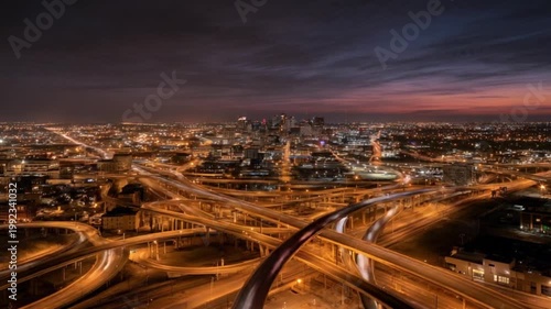 Cityscape view of lighted freeway overpasses leading to a lit city skyline at dusk