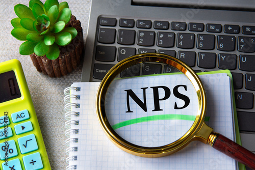 NPS acronym in notebook under magnifying glass with laptop and calculator in background