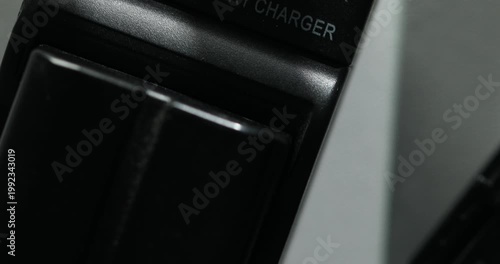 Close-up of black battery charger with red indicator light on
