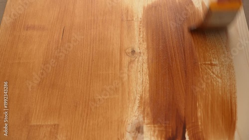 Hand brushing wood finish across tabletop during indoor renovation work.