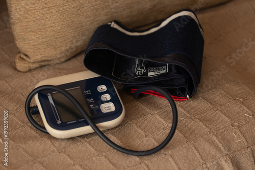 Fotografía Home Healthcare -Automatic blood pressure monitor with arm cuff resting on a sofa, symbolizing accessible, self-managed healthcare and medical wellness in everyday domestic life