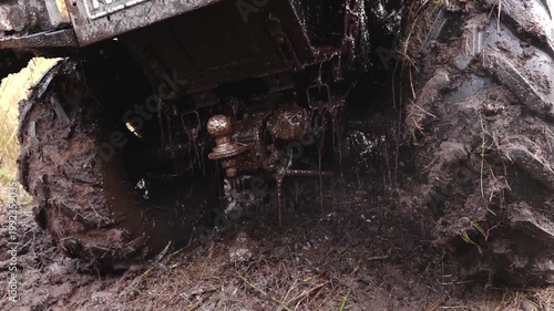 Six-wheeled ATV navigating through muddy terrain, showcasing tire details and mud splashes in a natural outdoor setting