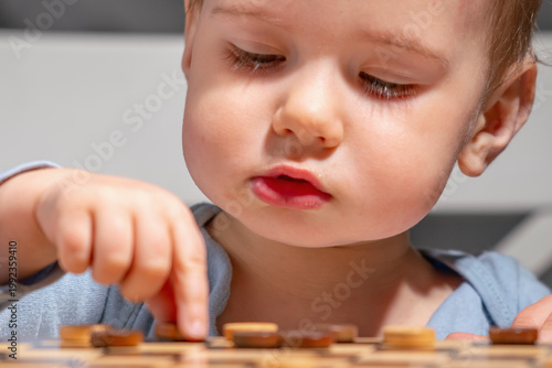 Adorable kid focused on board game, concept of early intelligence and learning.