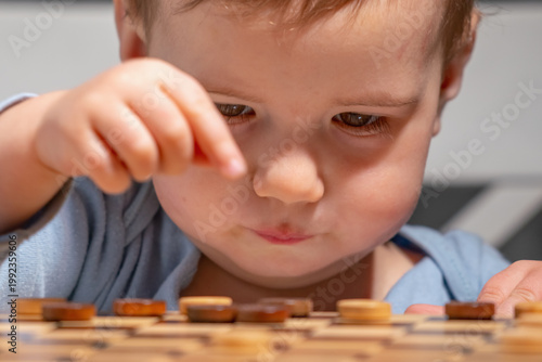 Focused toddler playing checkers, making a decision while learning through play.