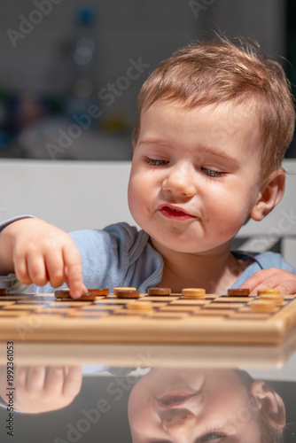 Young boy learning through play, engaging with classic board game.