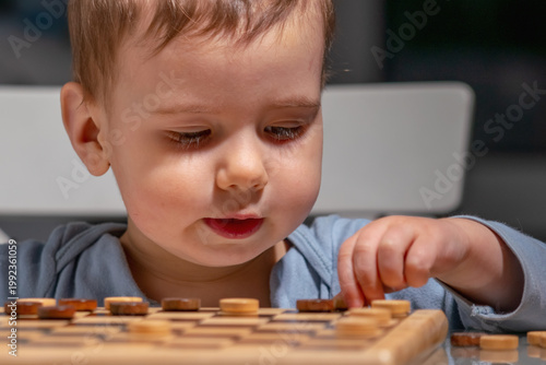 Toddler exploring checkers board, showing curiosity and discovery.