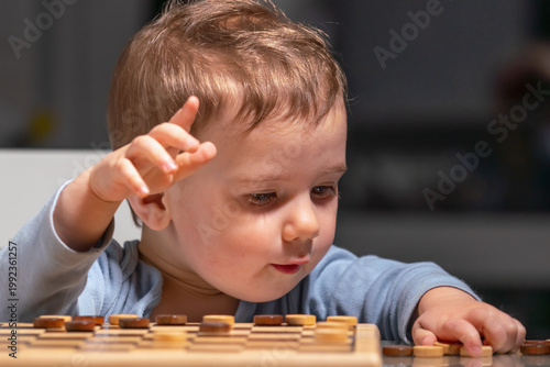 Toddler interacting with wooden board game, symbol of childhood learning.