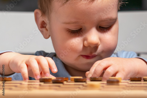 Child touching checkers pieces, exploring logic and strategy in a playful way.