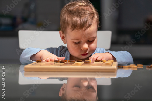 Little boy focused on checkers board, developing concentration and thinking skills.