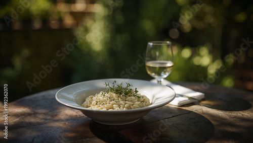 Creamy risotto dish with white wine served on a rustic outdoor table with italian food with wine glass with outdoor dining with al fresco with dining experience with food photography with comfort food