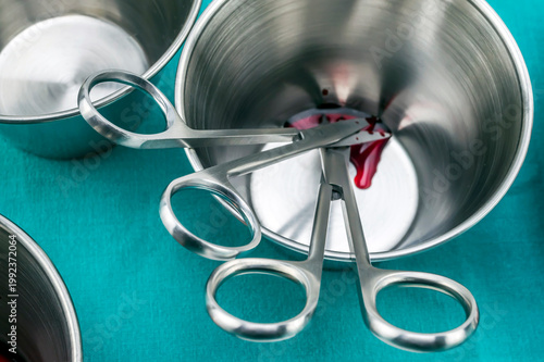 Several suture scissors on a silver tray, traces of blood, conceptual image, horizontal composition