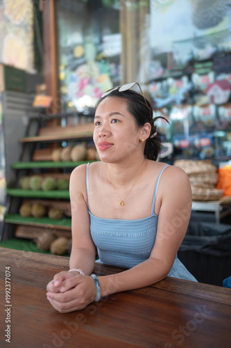 Young Asian Woman Enjoying a Relaxing Moment at a Vibrant Durian Market