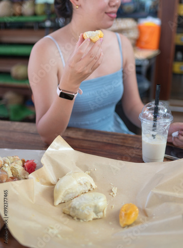 Young Woman Enjoying Durian Delicacies at a Bustling Market Buffet