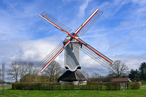Windmill De Leystermolen (Mol, Belgium) in a rural landscape with green grass and cloudy sky, combining classical architecture and functionality.