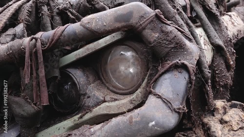 Close-up view of weathered mechanical components partially buried in dirt, showcasing intricate details of rust and decay in an outdoor setting