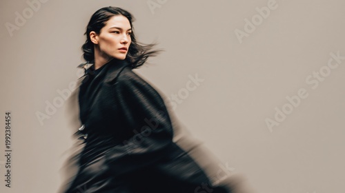 Stylish woman in motion blur running in dark coat against beige background with copy space, modern fashion portrait for dynamic advertising design