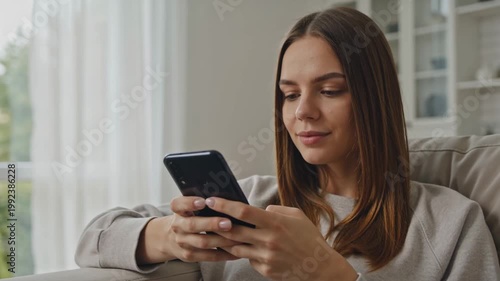 Young woman using smartphone while sitting on sofa at home  
