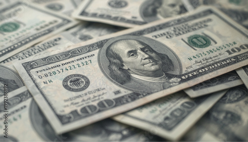 Currency notes in denominations of one hundred dollars lie scattered across a flat wooden desk surface.