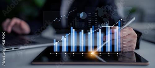 Foto A business professional is using a tablet to analyze financial data displayed through interactive graphs and charts, illustrating market trends and success